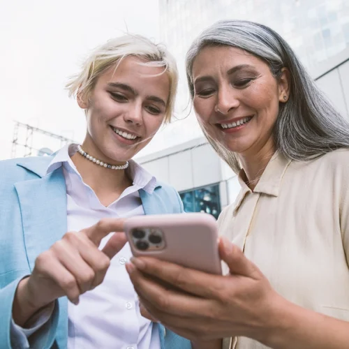 2 Frauen schauen lächelnd auf ein Handy