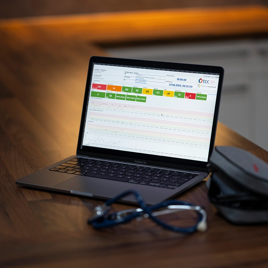 Aufgeklappter Laptop mit offener Website auf Schreibtisch stehend und daneben ein Etui und ein Stethoskop.