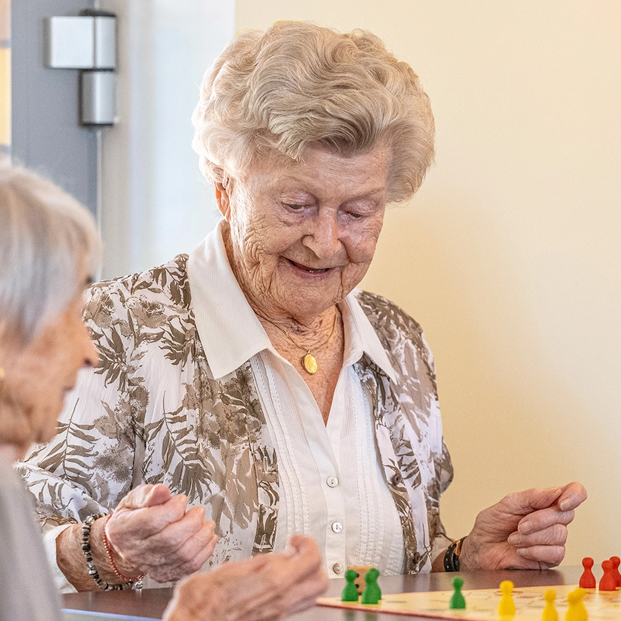 Zwei Klientinnen sitzen am Tisch und spielen Mensch ärgere dich nicht.